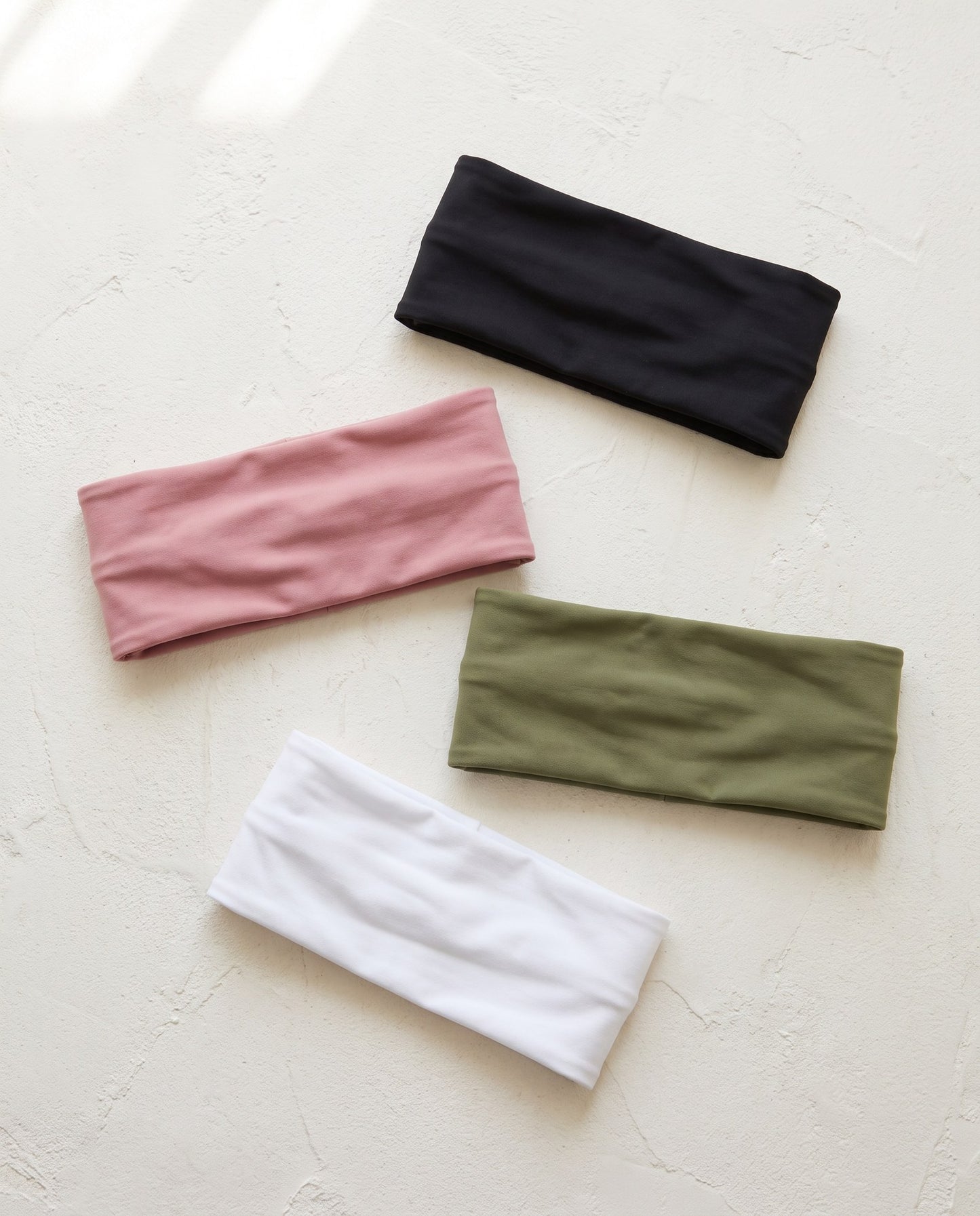 Quattro fasce per capelli in nylon tinta unita nei colori nero, rosa, verde e bianco